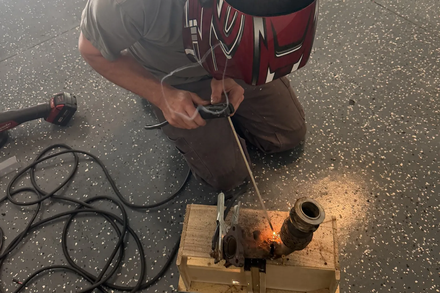 Tony welding a vehicle component with his tools beside him
